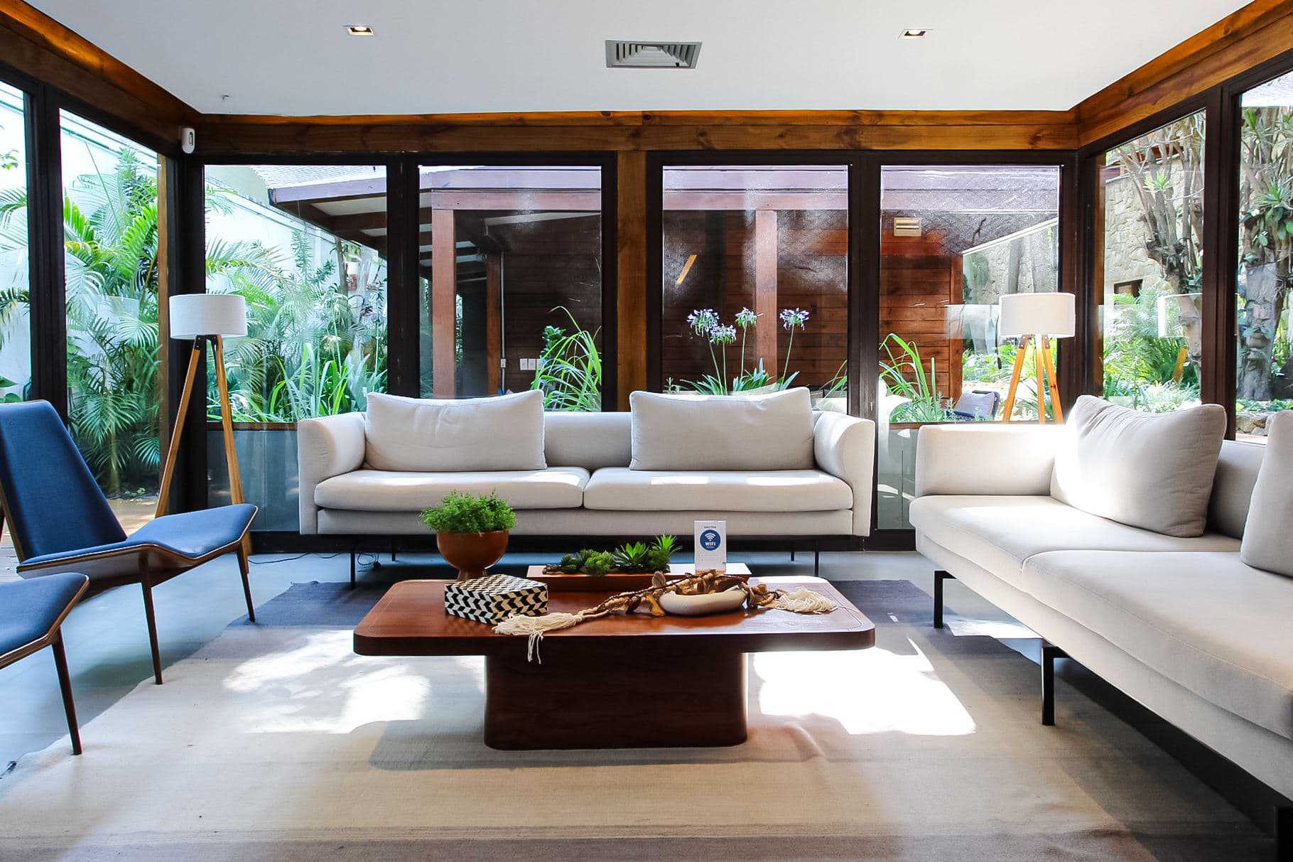 Lounge da Oxy Recovery com sofás brancos e abertura para jardim tropical — ambiente acolhedor onde começa a conversa.